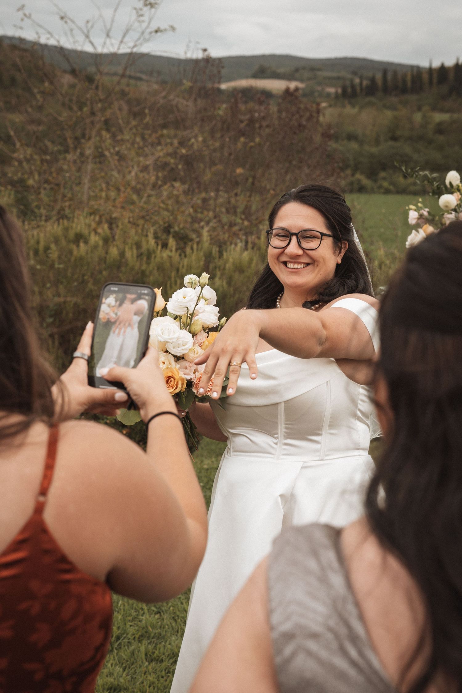 A wedding guest takes a photo of a ring on display during an outdoor celebration.