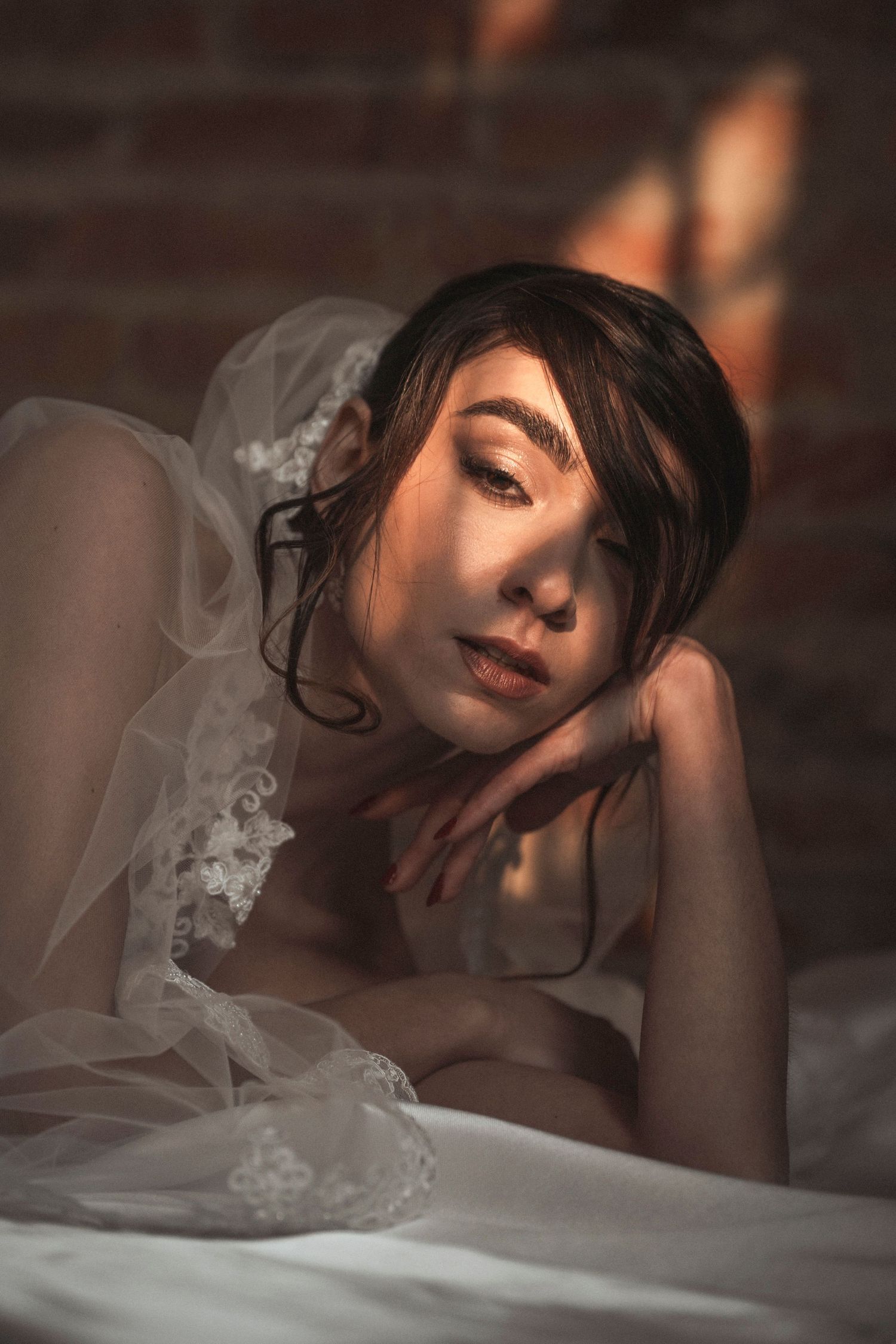 Dreamy boudoir photography with soft lighting and delicate lace details against dark background.