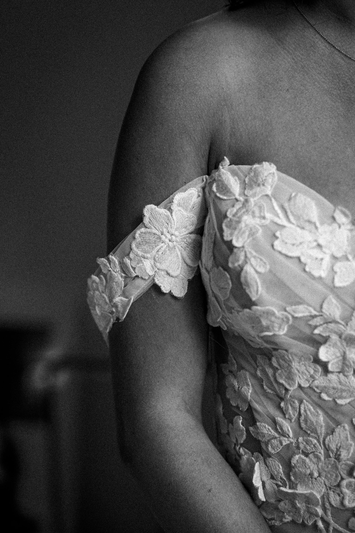 Close-up detail of delicate white lace applique on wedding dress.