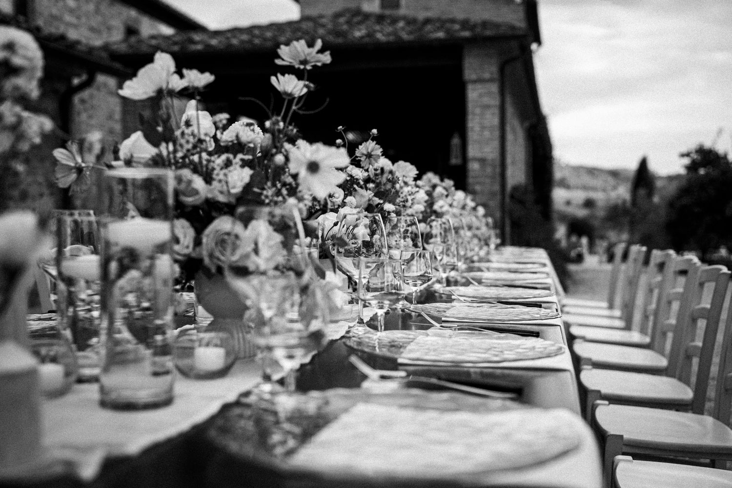 Elegant black and white table setting with floral centerpieces at an outdoor wedding reception.
