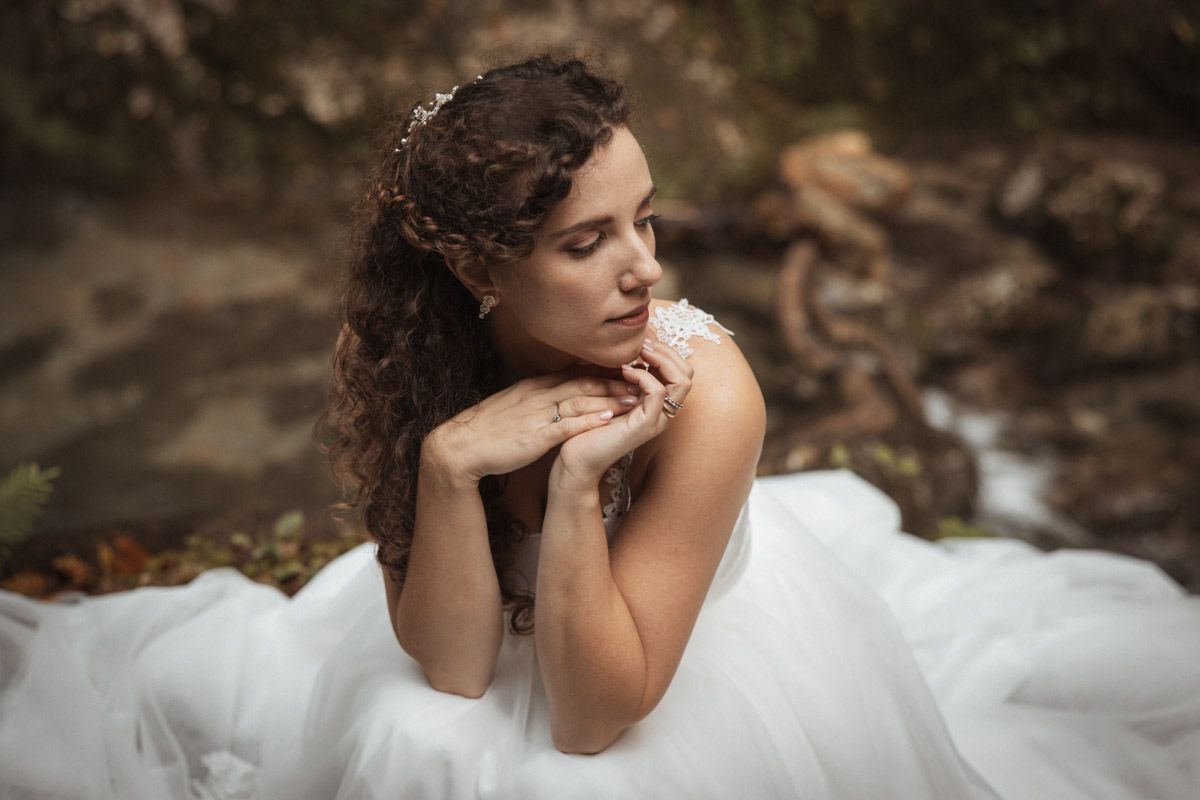 Ethereal bridal portrait showing a flowing white dress against natural woodland scenery.