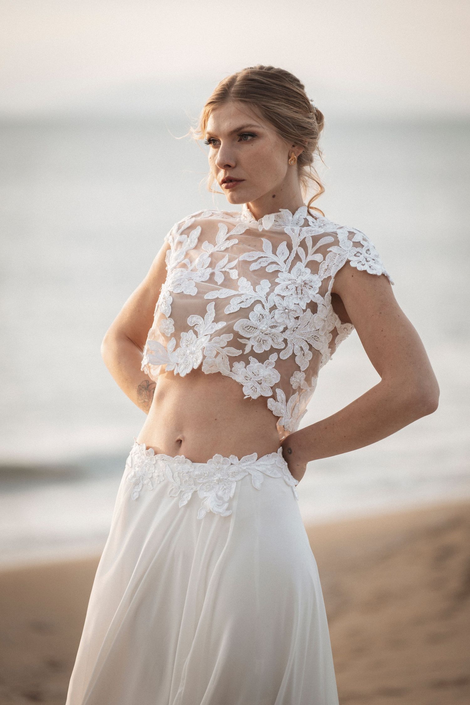 A delicate white lace wedding dress with floral appliques photographed against a soft light background.