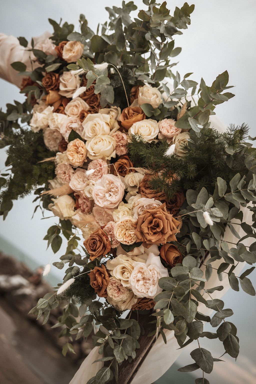 Elegant bouquet featuring peach garden roses and fresh eucalyptus leaves against a light background.