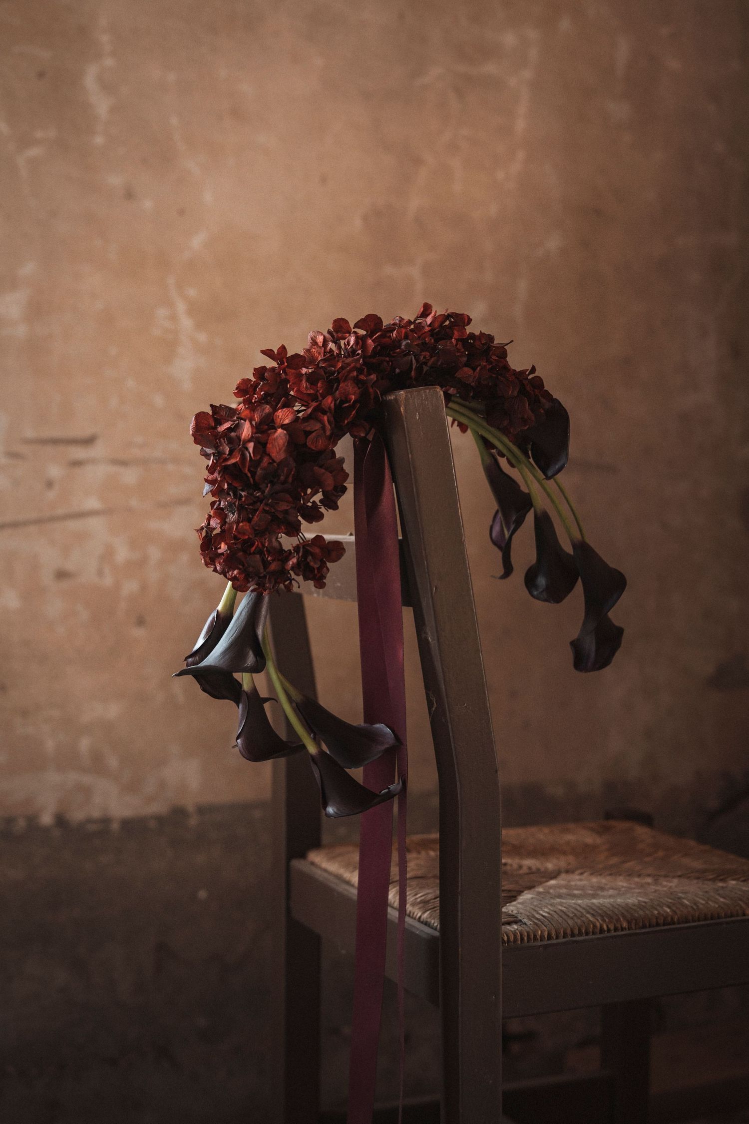 A sequence of images showing dried red flowers drooping over dark pedestals against a textured brown wall.