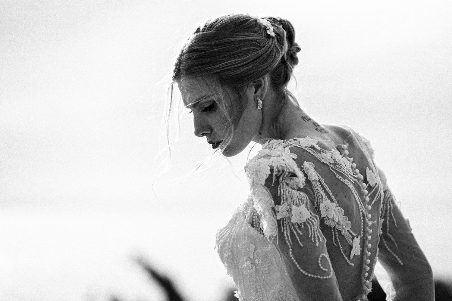 A bride in a lace wedding dress gets ready for her ceremony, shown in an artistic black and white photograph.