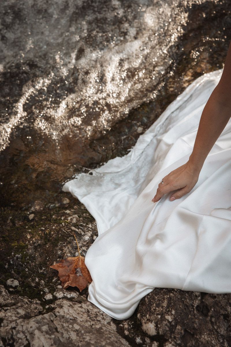 Detail shot of a white wedding dress flowing over textured rocky terrain.