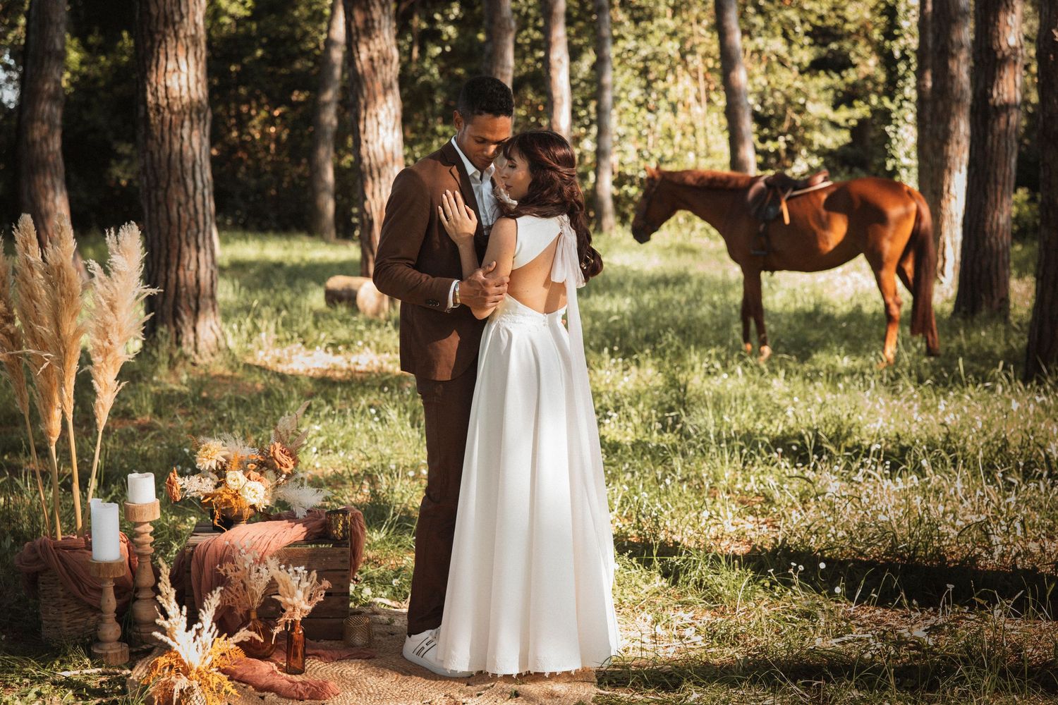 A couple shares a tender moment in a sunlit forest clearing during their wedding photoshoot.