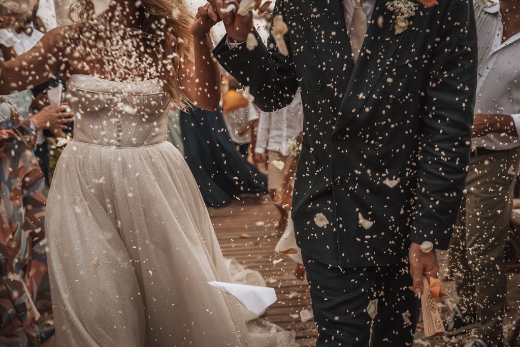 Black and white photo of wedding guests throwing confetti during celebration.