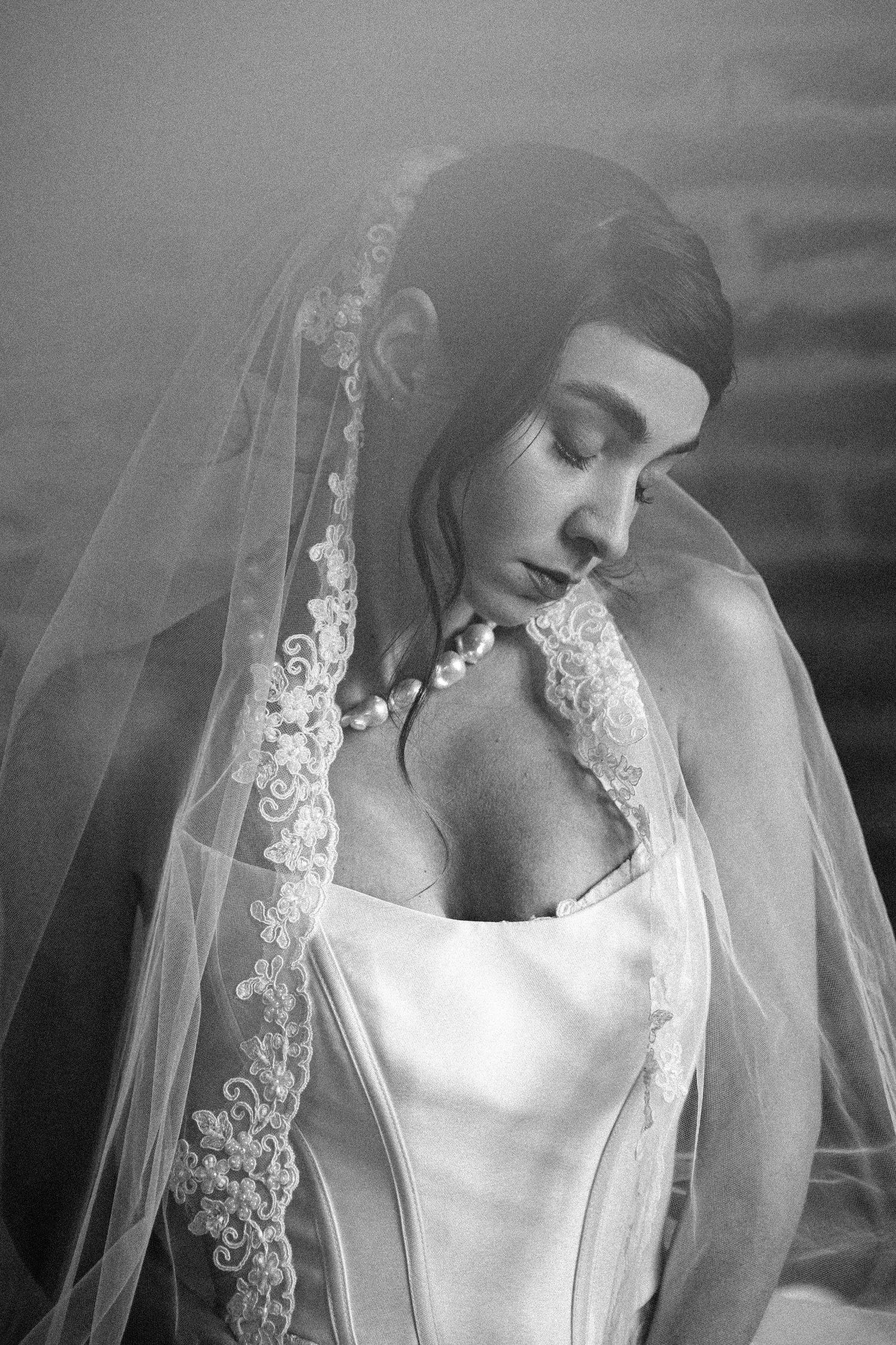 Ethereal black and white bridal portrait showcasing delicate lace veil details.