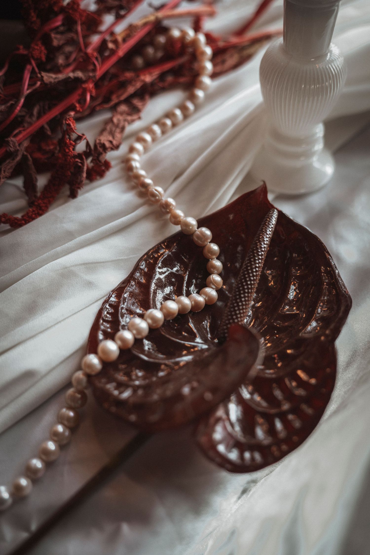 Pearl necklace draped elegantly over vintage brown decorative objects with delicate details.
