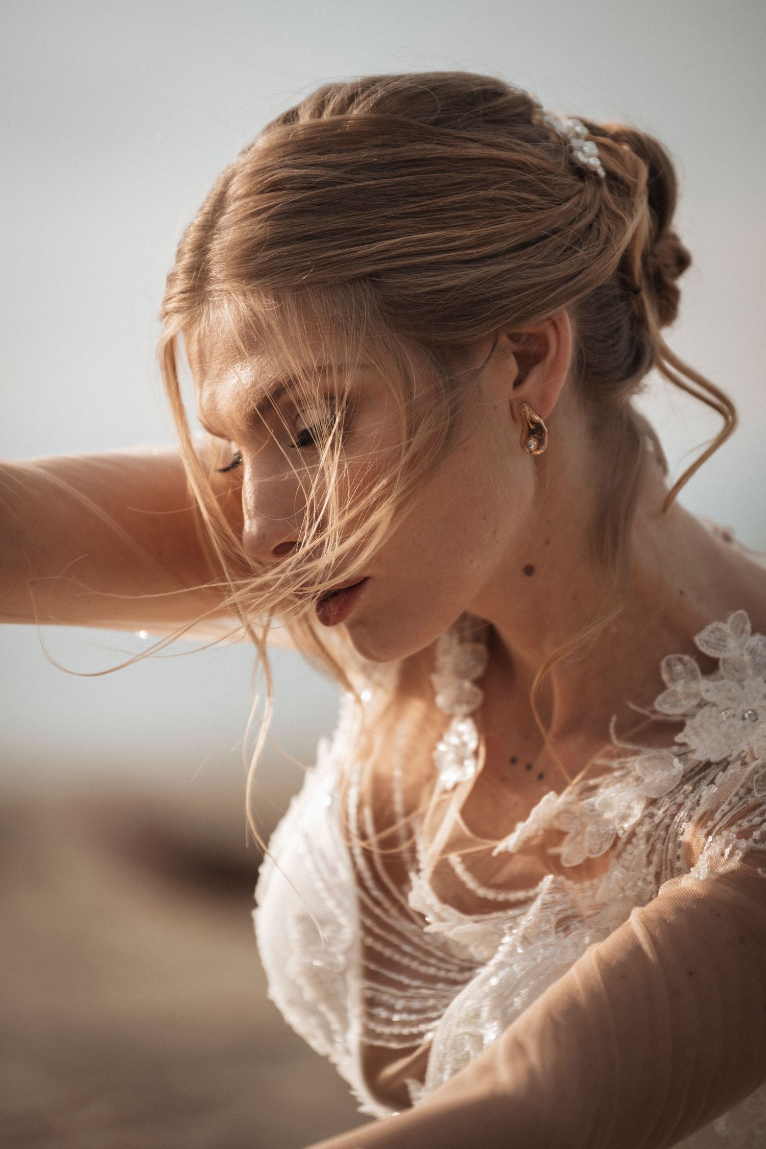 A romantic bridal portrait in soft lighting shows delicate lace details and an elegant updo hairstyle.