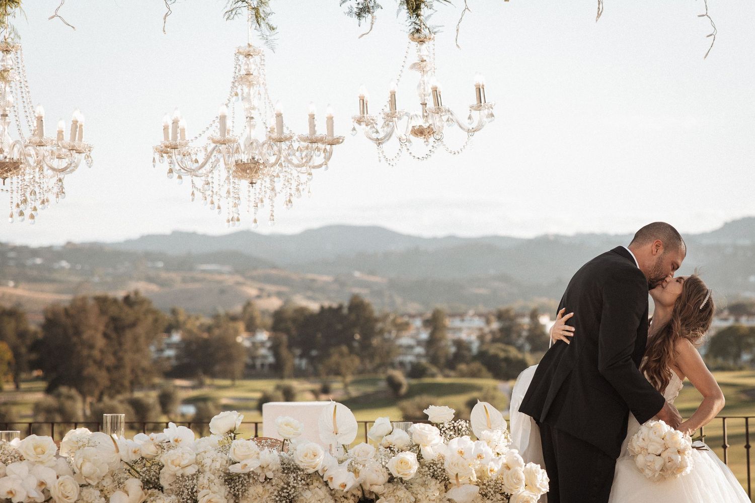 Romantic outdoor wedding ceremony setup with white floral arrangements and mountain views.