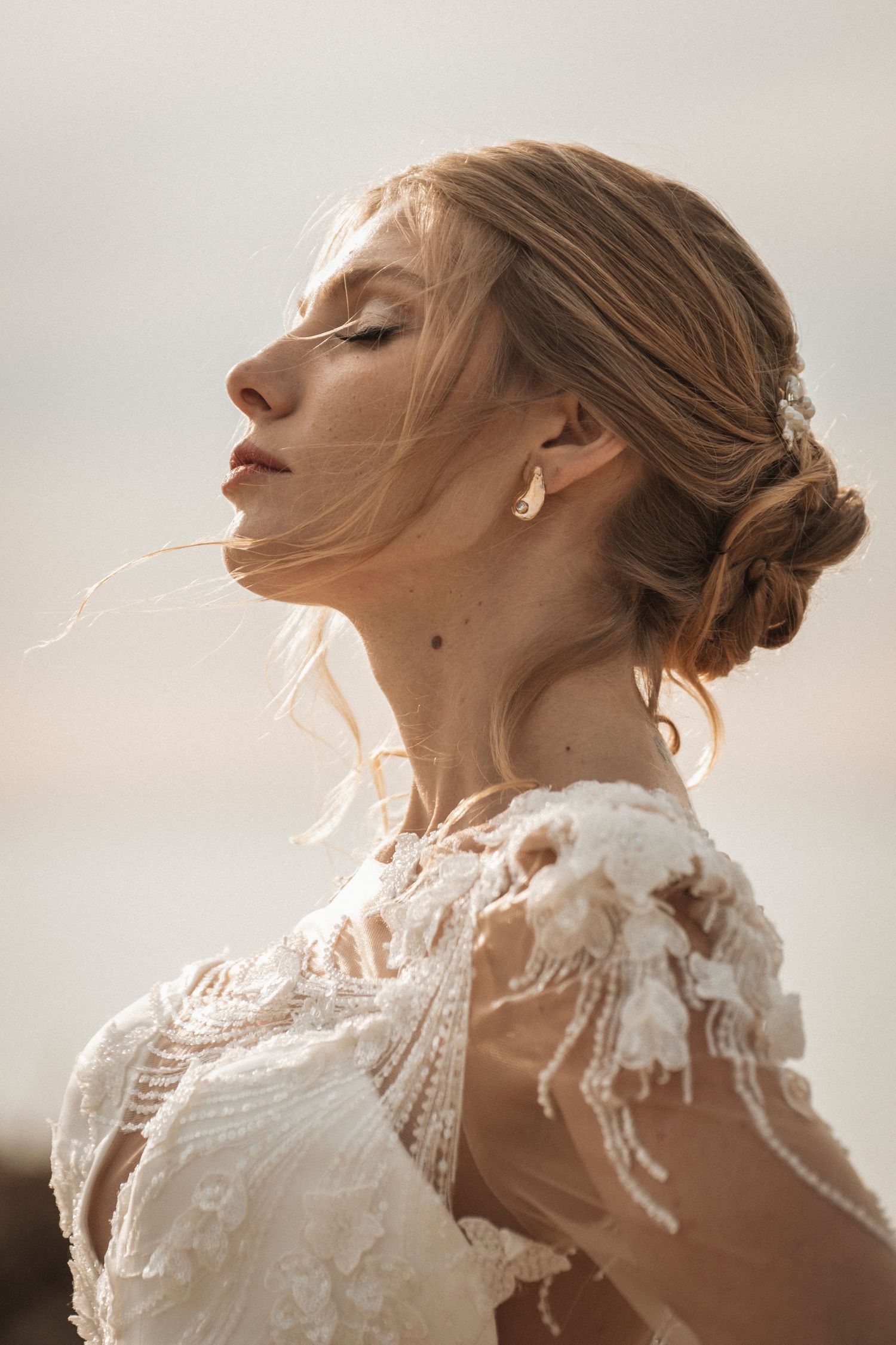 Close-up profile shot showcasing elegant bridal updo and intricate lace wedding dress details.