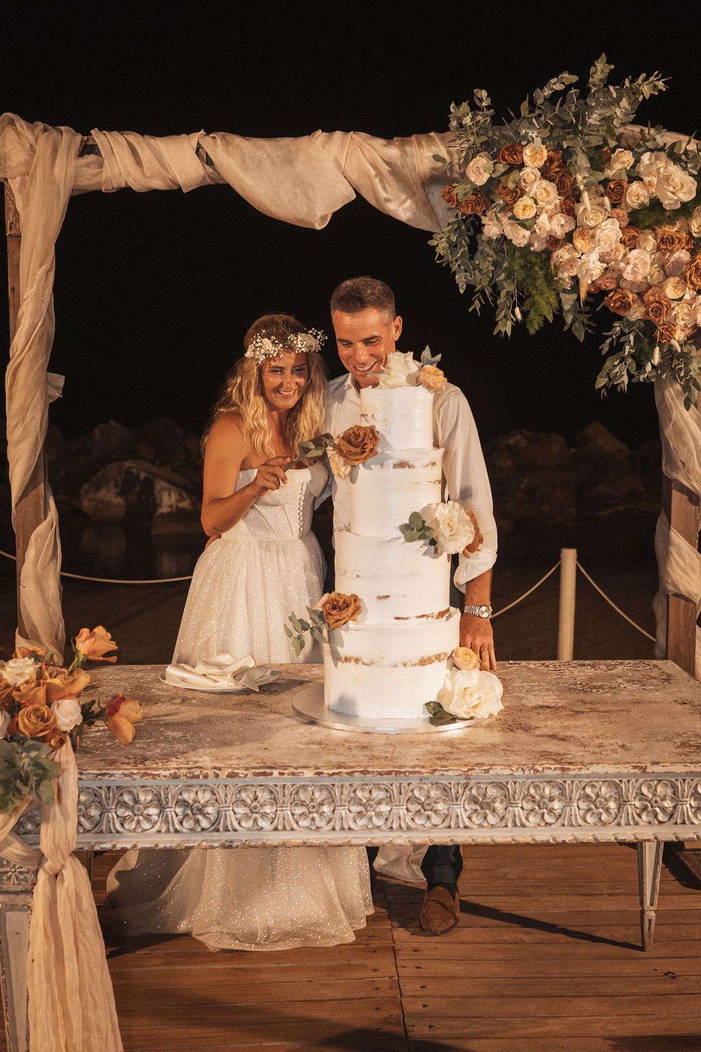 Elegant wedding cake display with floral decorations on rustic wooden table.