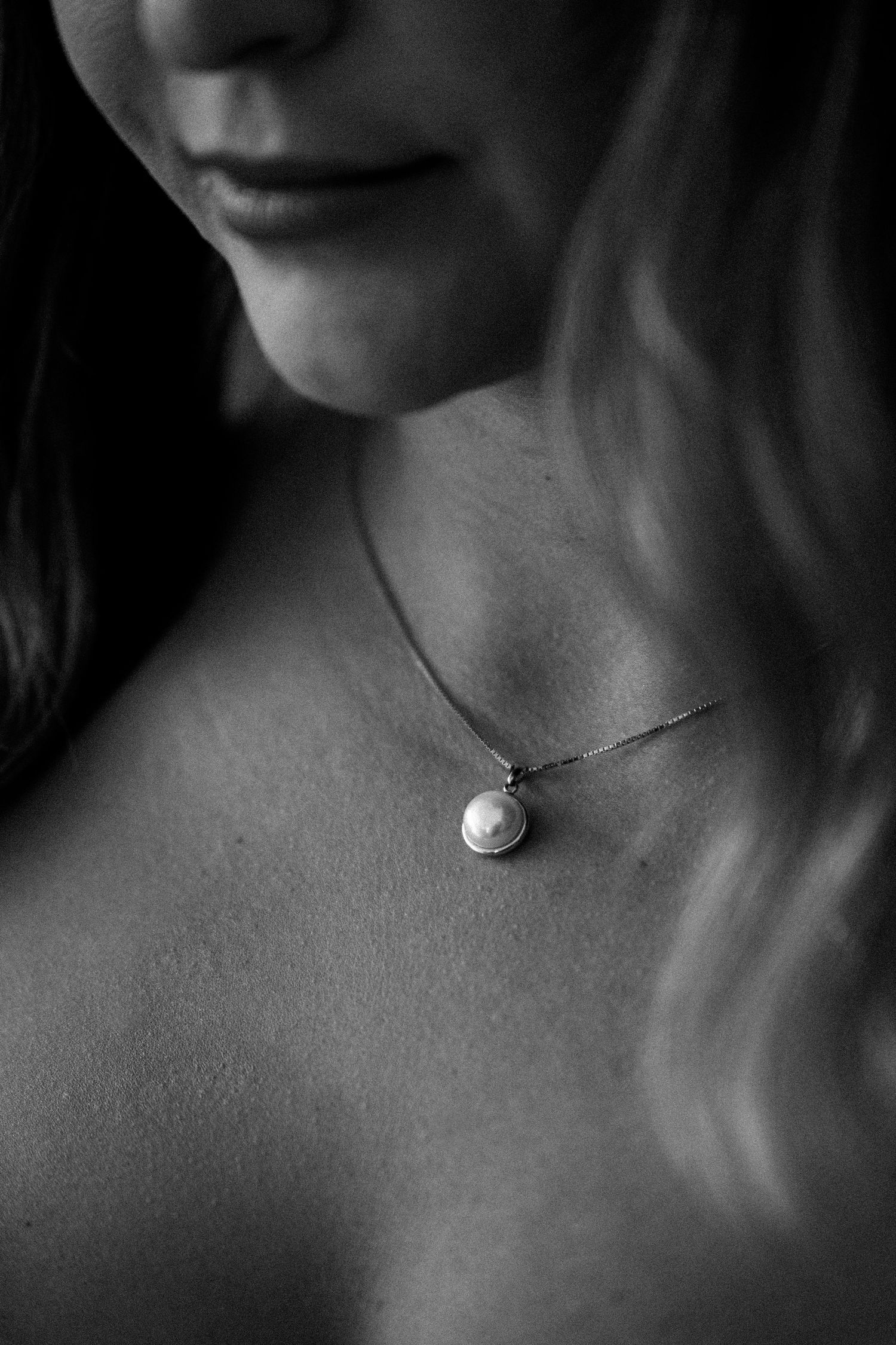 Artistic black and white portrait showing a delicate necklace on a neck.