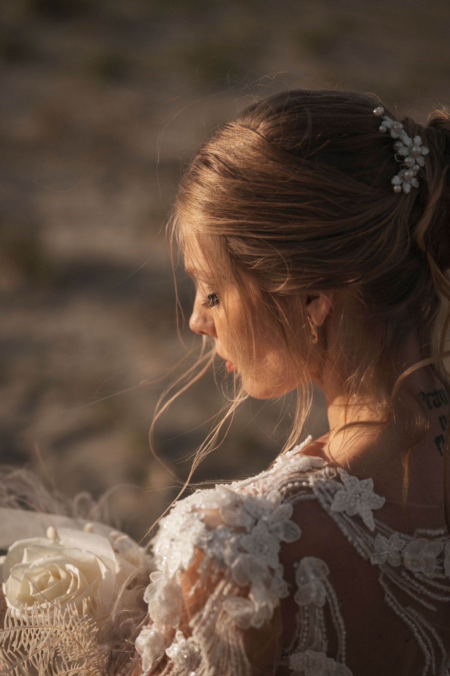 Delicate lace details on a wedding dress captured in warm golden light against a desert backdrop.