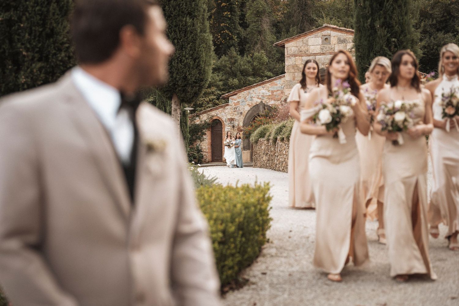 Wedding party walking in a garden setting wearing champagne colored dresses and formal attire.