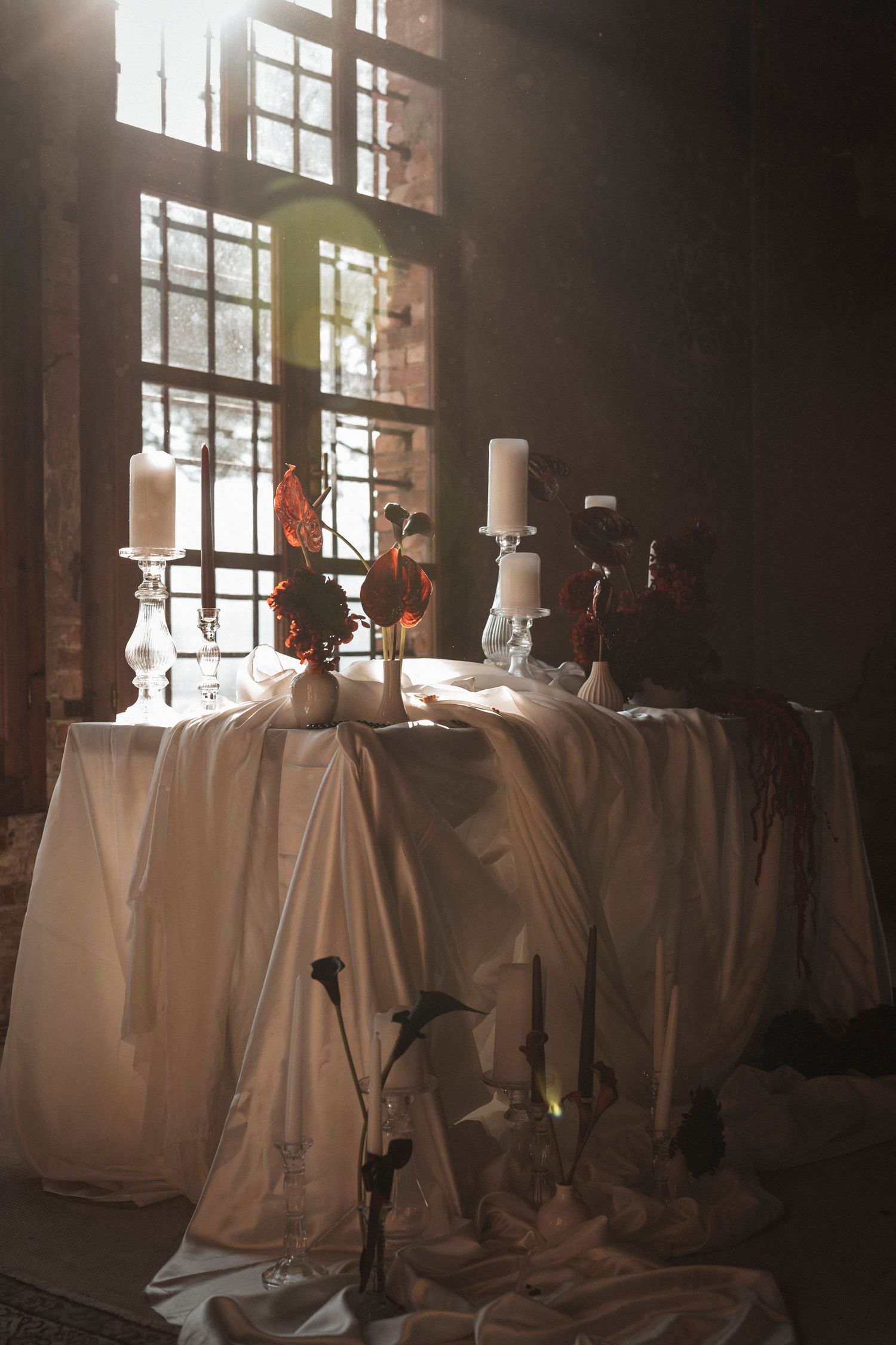 White fabric drapes elegantly across a dimly lit room with sunlight streaming through windows.