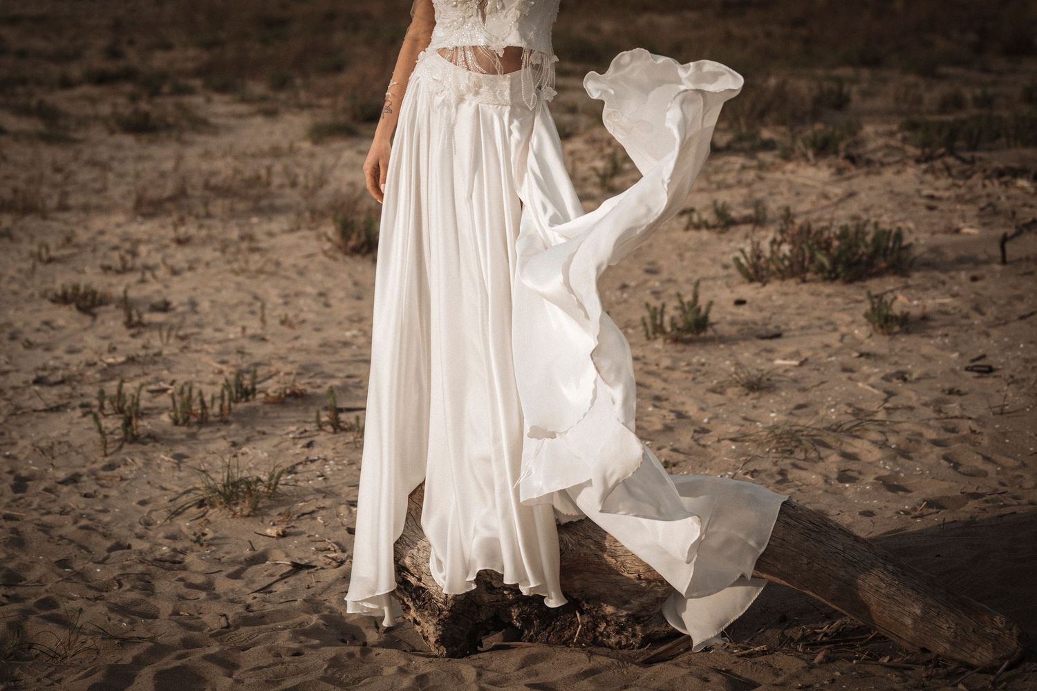 A flowing white dress billows in the wind against a rustic outdoor backdrop creating an ethereal effect.