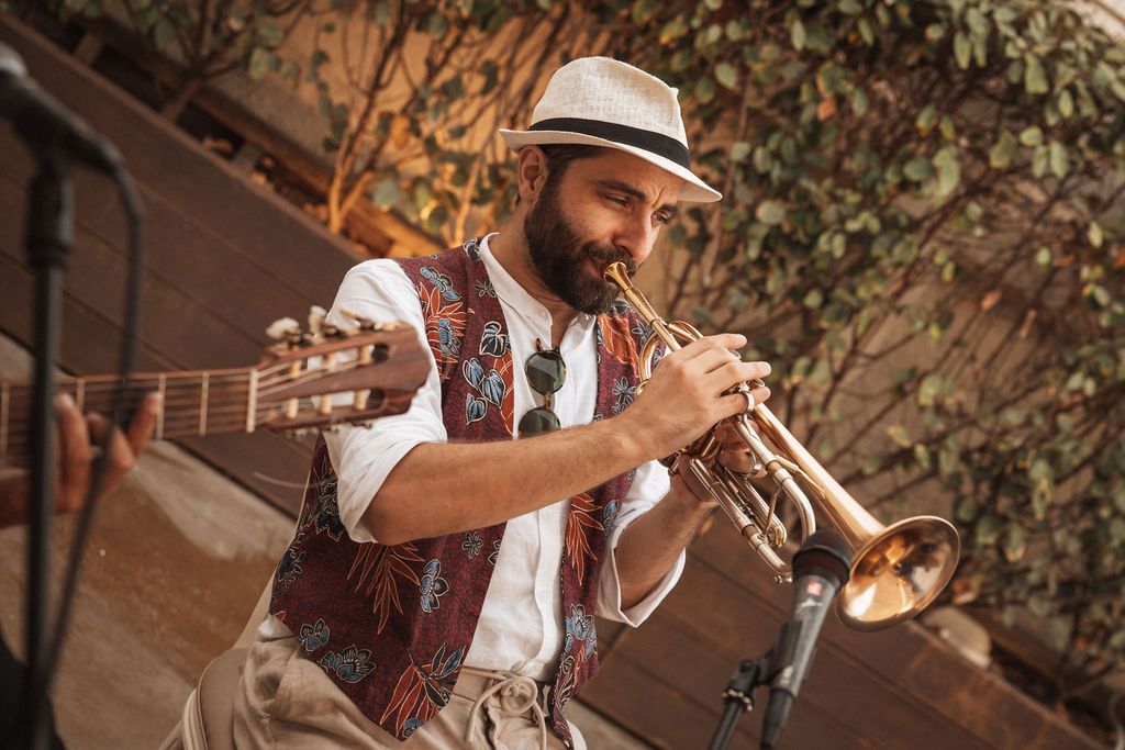 Musicians in casual attire performing outdoors at a sunset event.