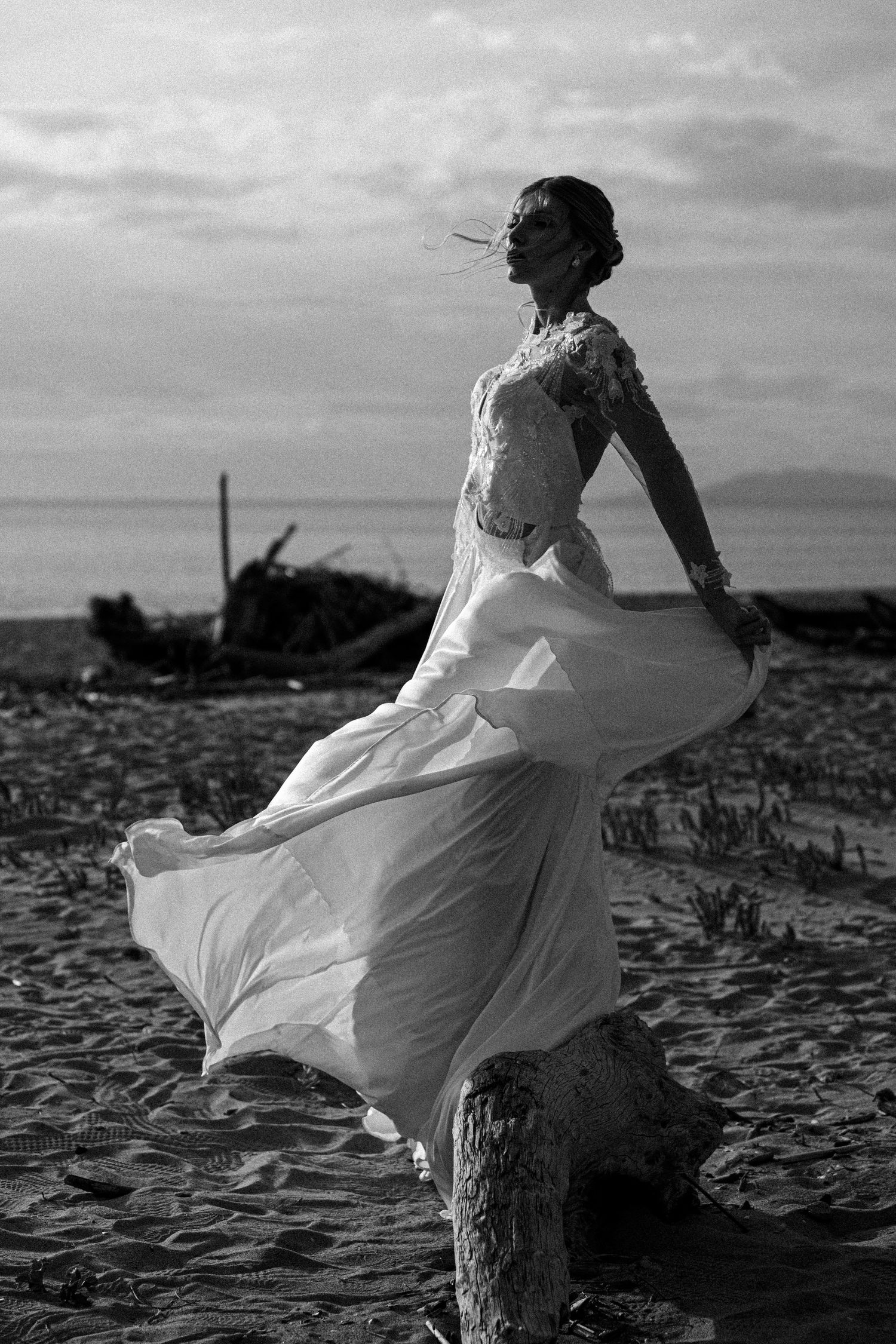 A white dress flows dramatically in the wind against a moody black and white landscape.