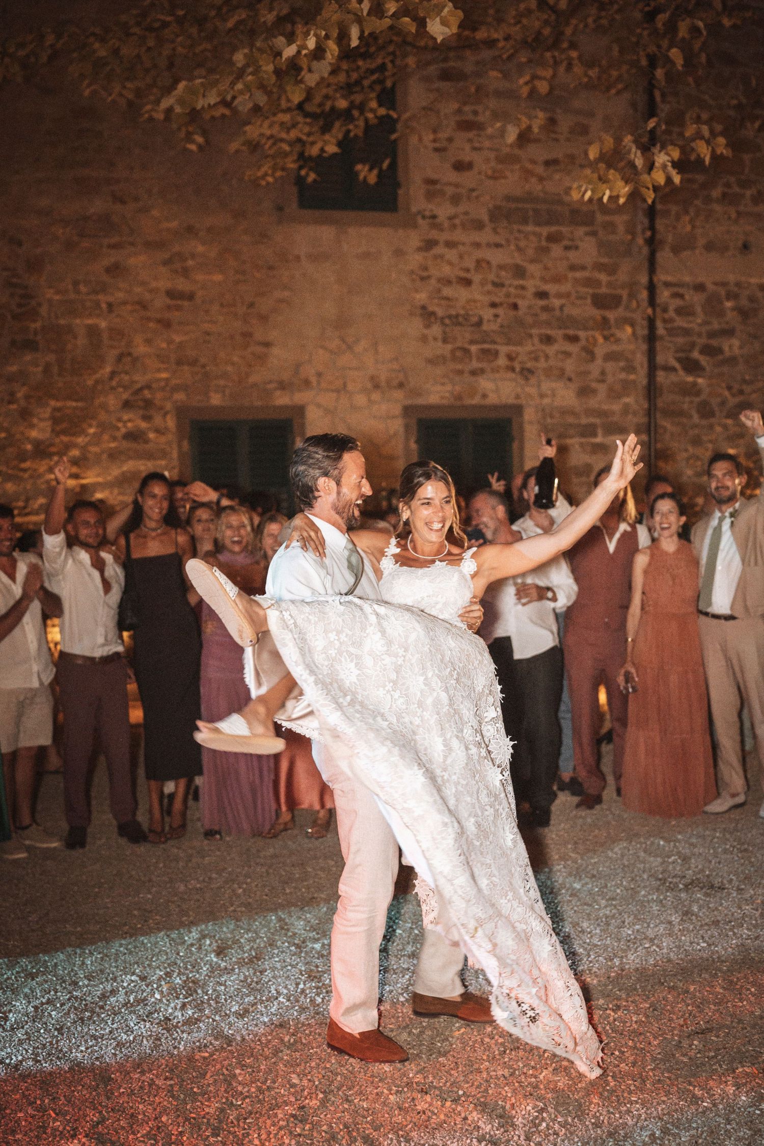 Wedding couple performing their first dance surrounded by guests in a rustic brick venue.