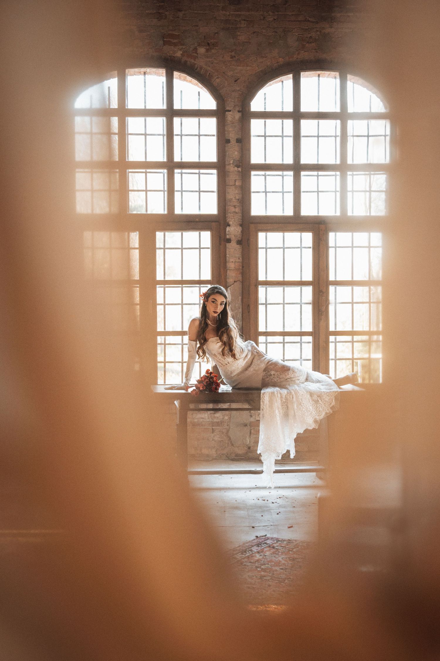Romantic bridal portraits in a rustic brick venue with arched windows and natural light streaming in.