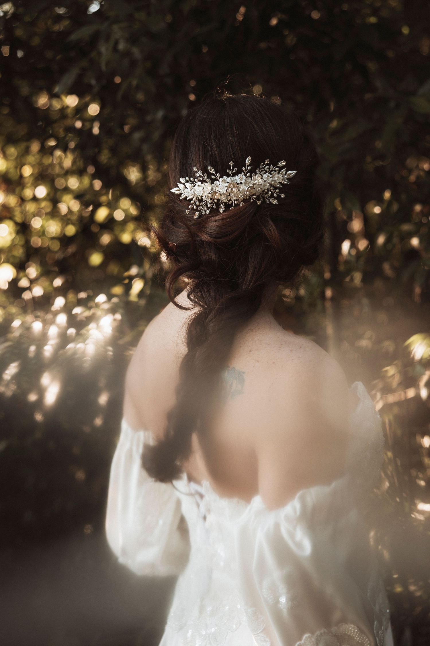 Back view of bride wearing crystal hair accessory with bokeh lights in background.