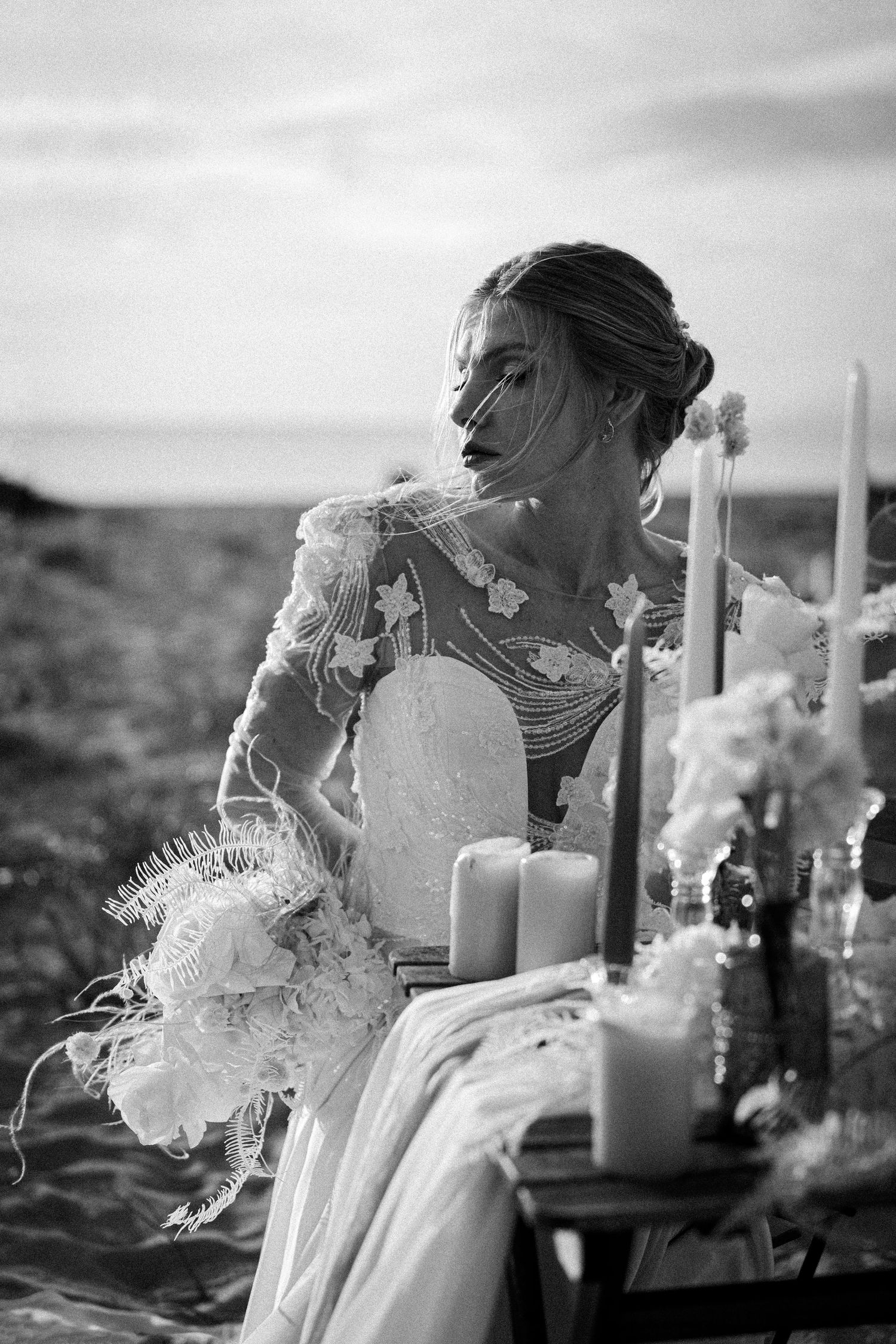 An elegant table setting with candles and a white dress creates a romantic black and white composition.