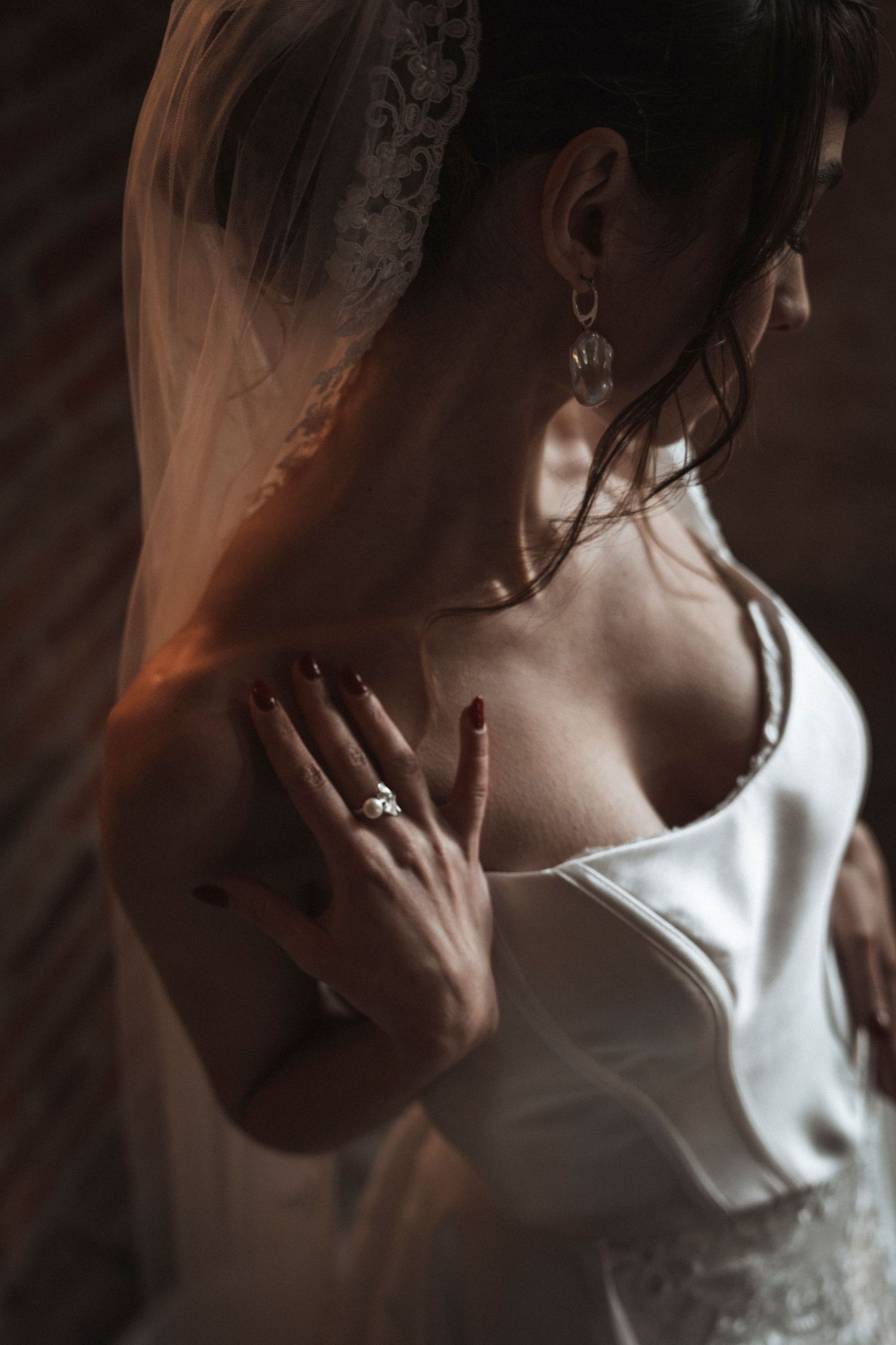 Artistic close-up portrait showing delicate veil details against a dark background.