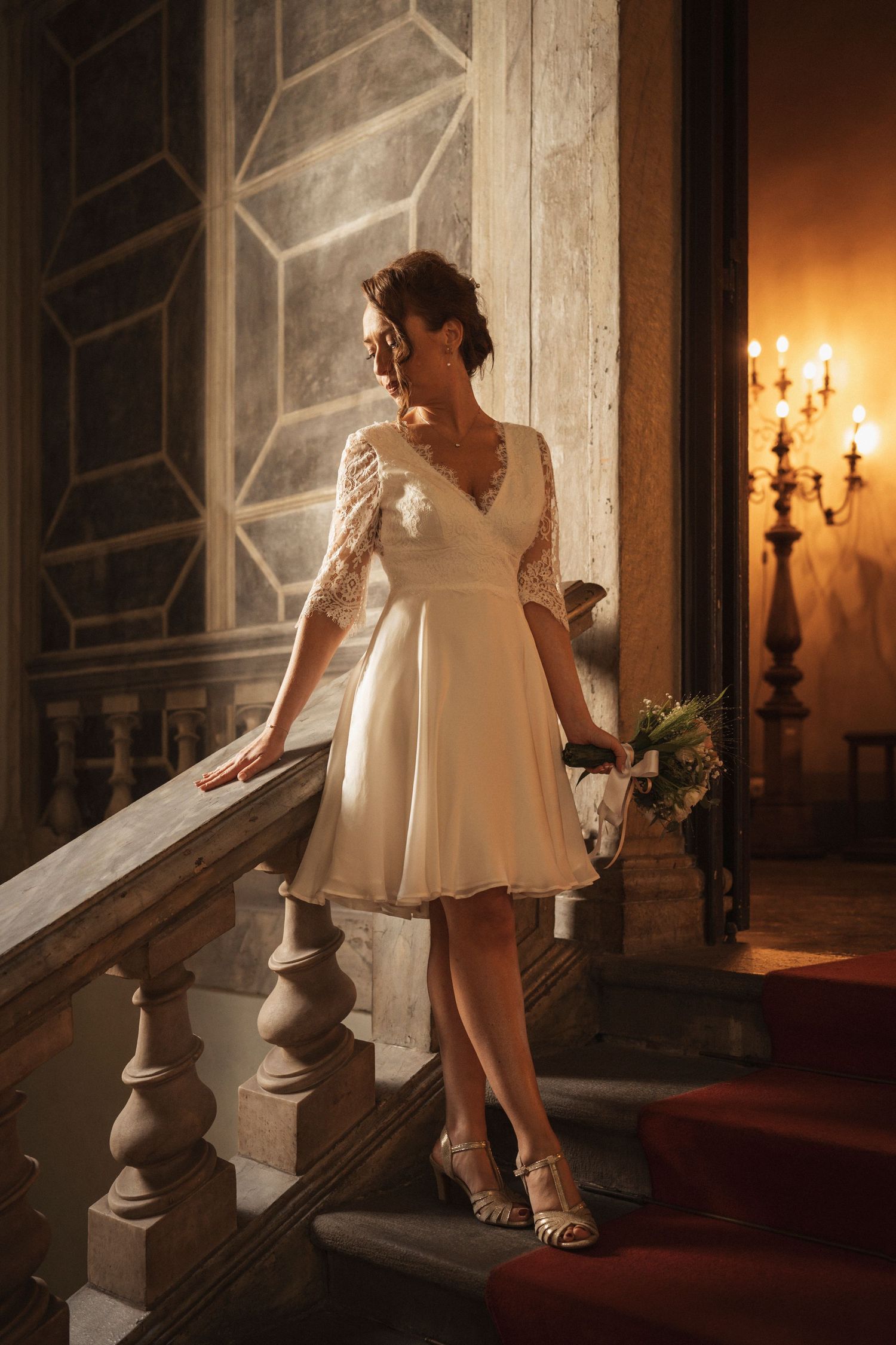 Person in white dress ascending elegant stone stairs in dramatic lighting.