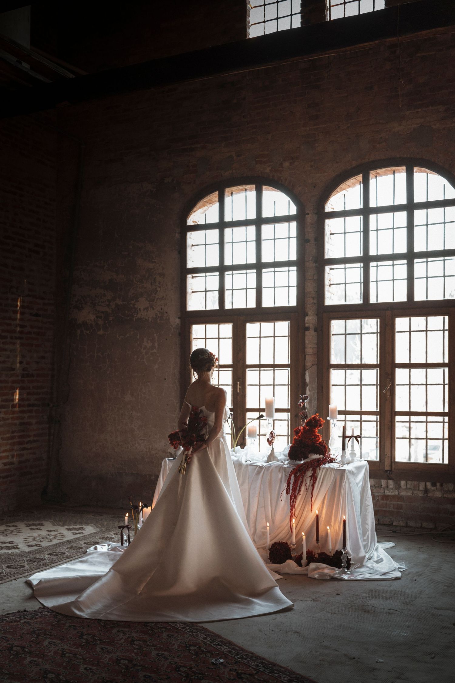 Artistic bridal photography in an industrial brick loft space with dramatic window lighting.