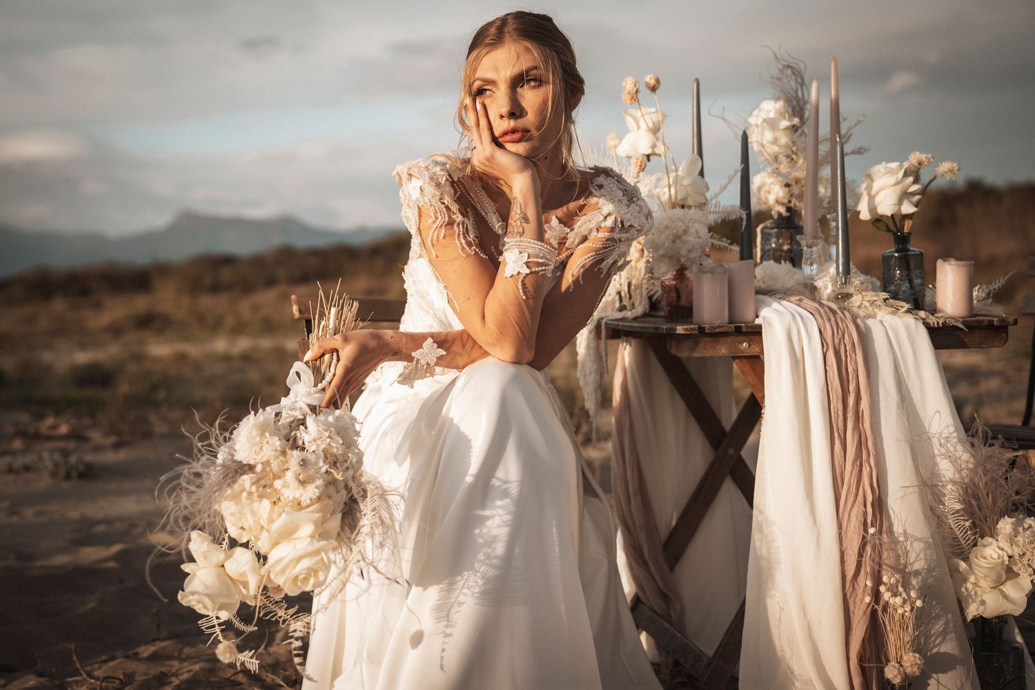 Ethereal bridal portrait with white floral arrangements and vintage styling in desert setting.