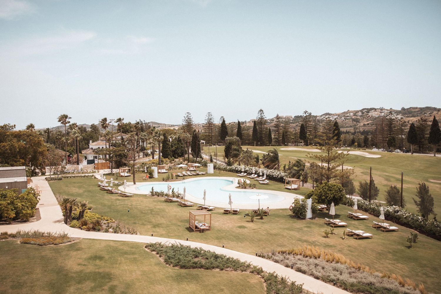 Panoramic view of a Mediterranean landscape with rolling hills and cypress trees.