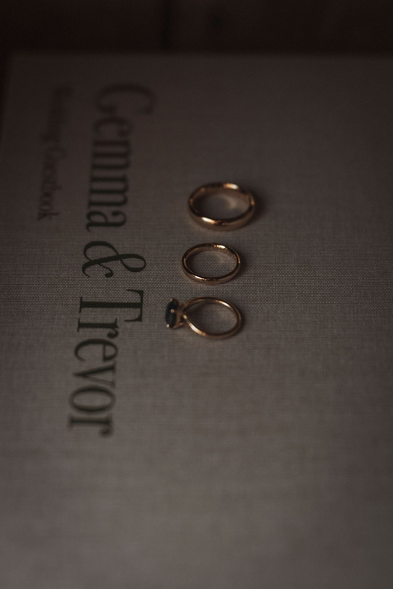 Wedding rings photographed on textured paper with dramatic lighting.