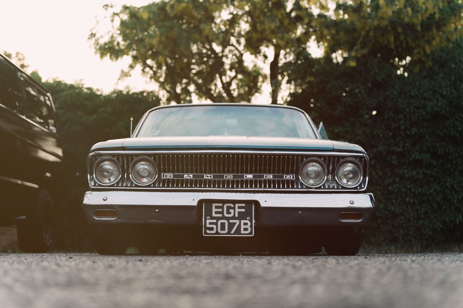 Vintage black Ford Galaxie with license plate EGF 507B parked on gravel, shot from low front angle at dusk.