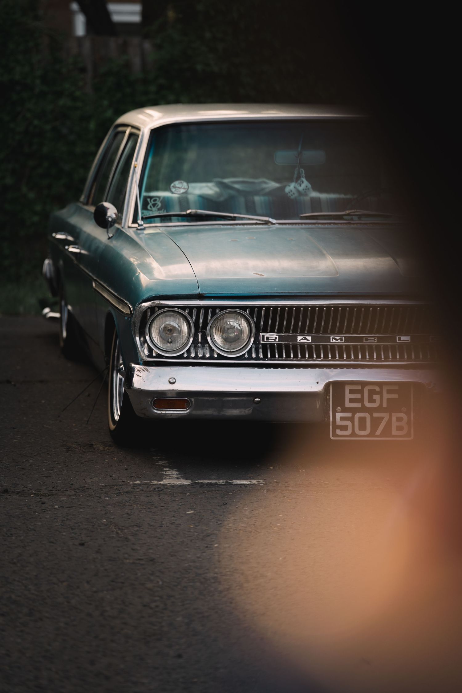 Vintage teal classic car with UK license plate EGF 507B parked on a dark street, shot with moody cinematic lighting.