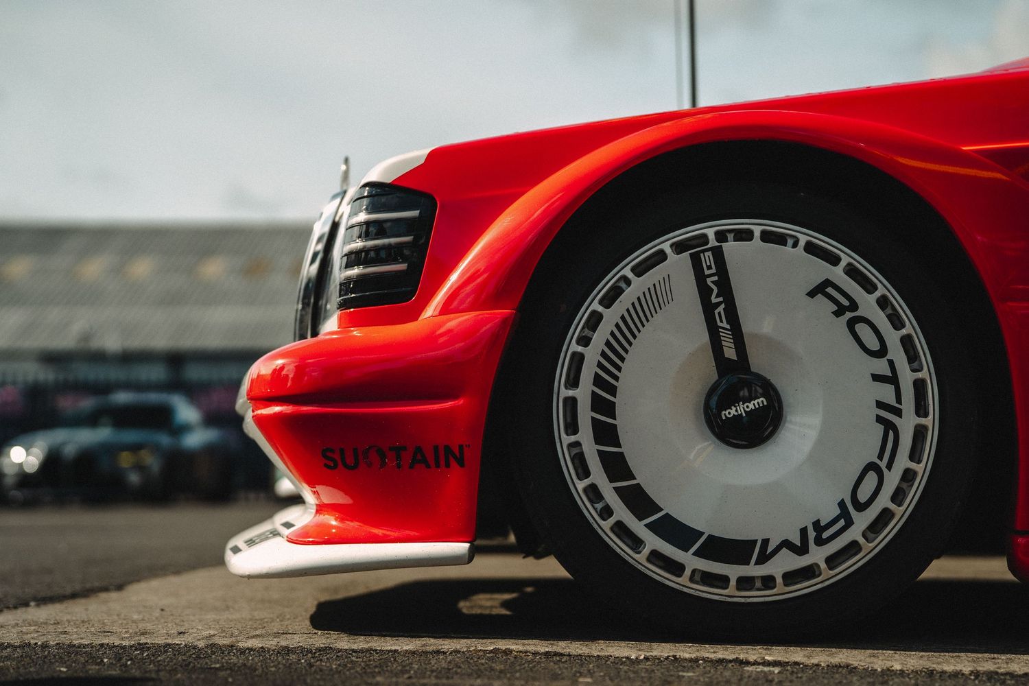 Red sports car with Rotiform alloy wheel and splitter detail at a car show.