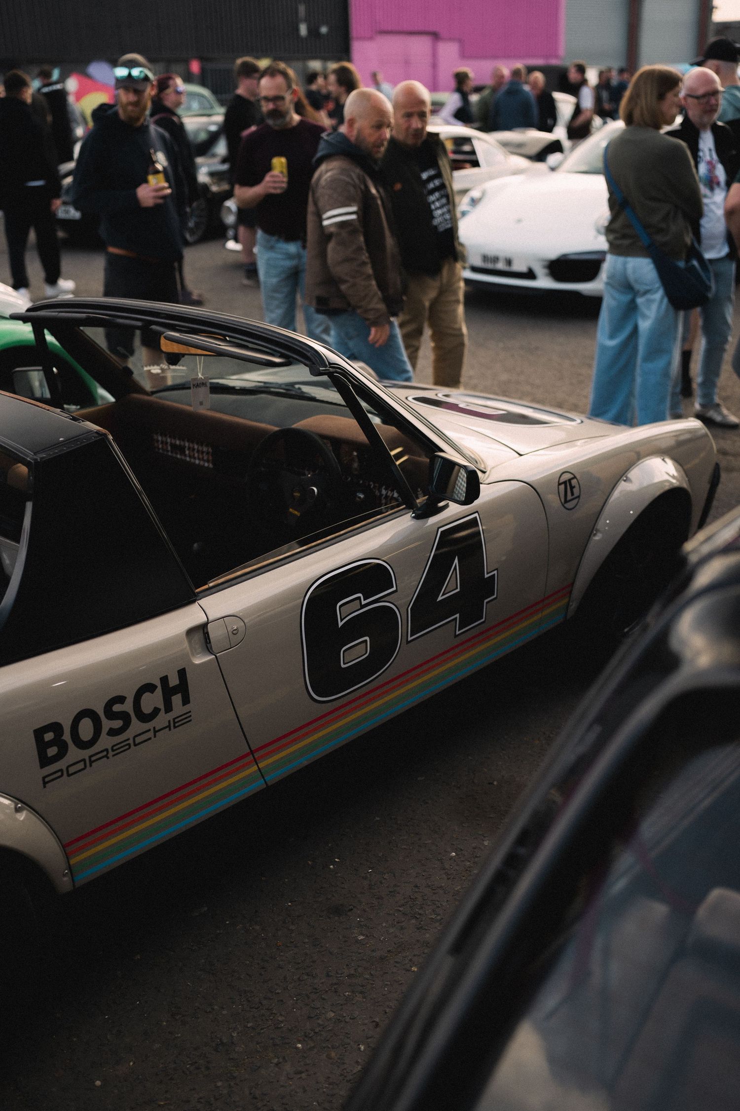 Vintage Porsche race car #64 with Bosch livery displayed at a car show event with spectators.