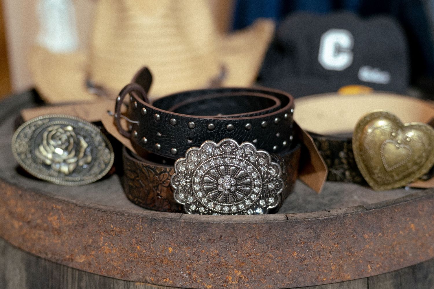 Dark brown studded leather belt with ornate silver concho buckle displayed on rustic wooden surface.