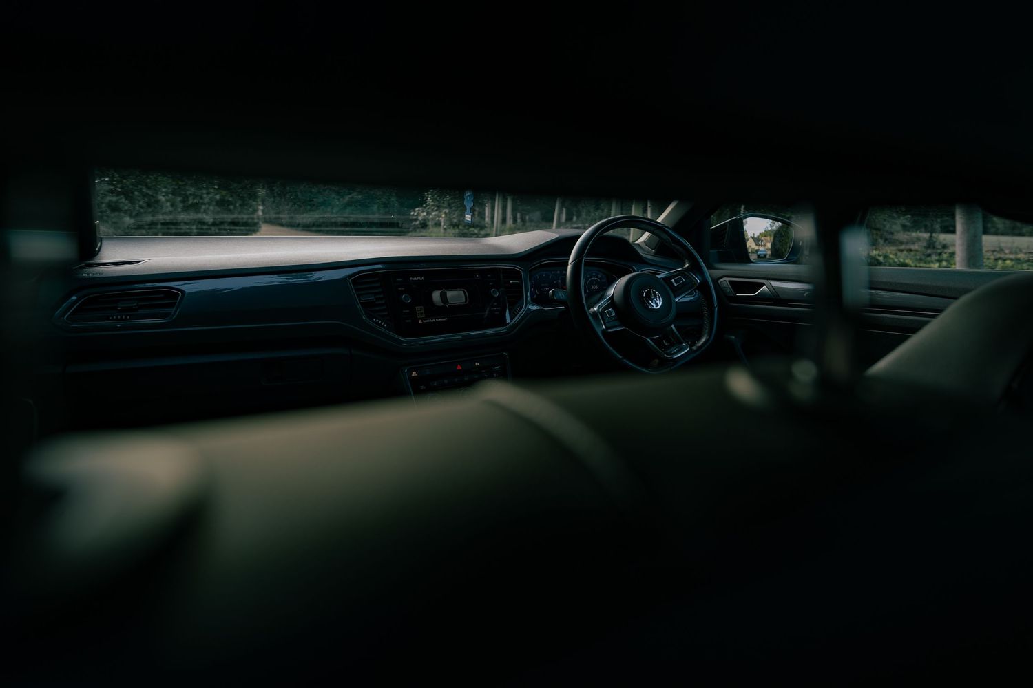 Interior view of a right-hand drive car dashboard and steering wheel in low light.