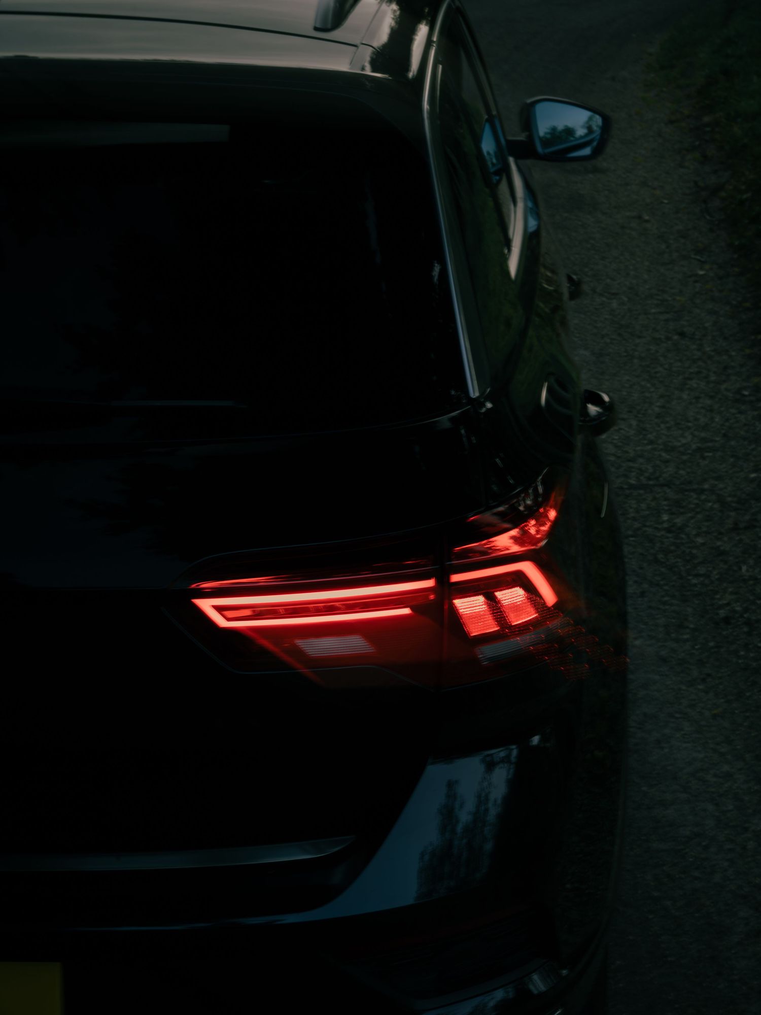 Close-up of glowing red LED tail lights on a dark black SUV at night.