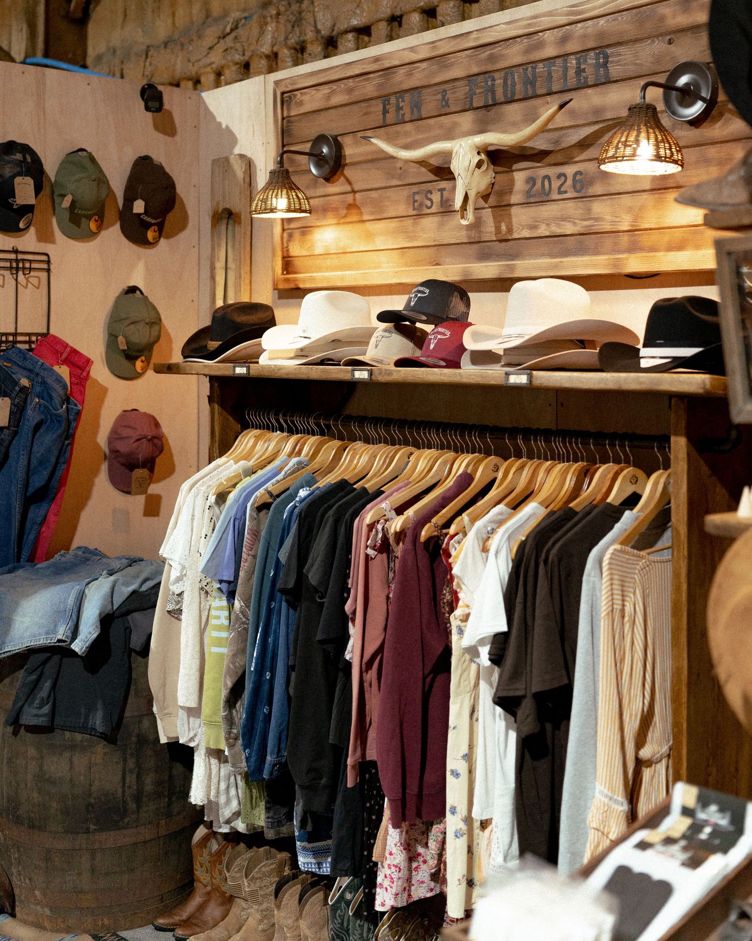 Rustic western clothing store with hats on display and colorful shirts on wooden rack, featuring vintage frontier decor.