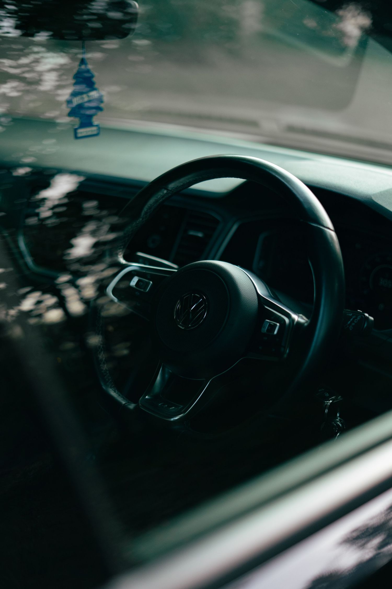 Interior shot of a Volkswagen steering wheel and dashboard viewed through the windshield.