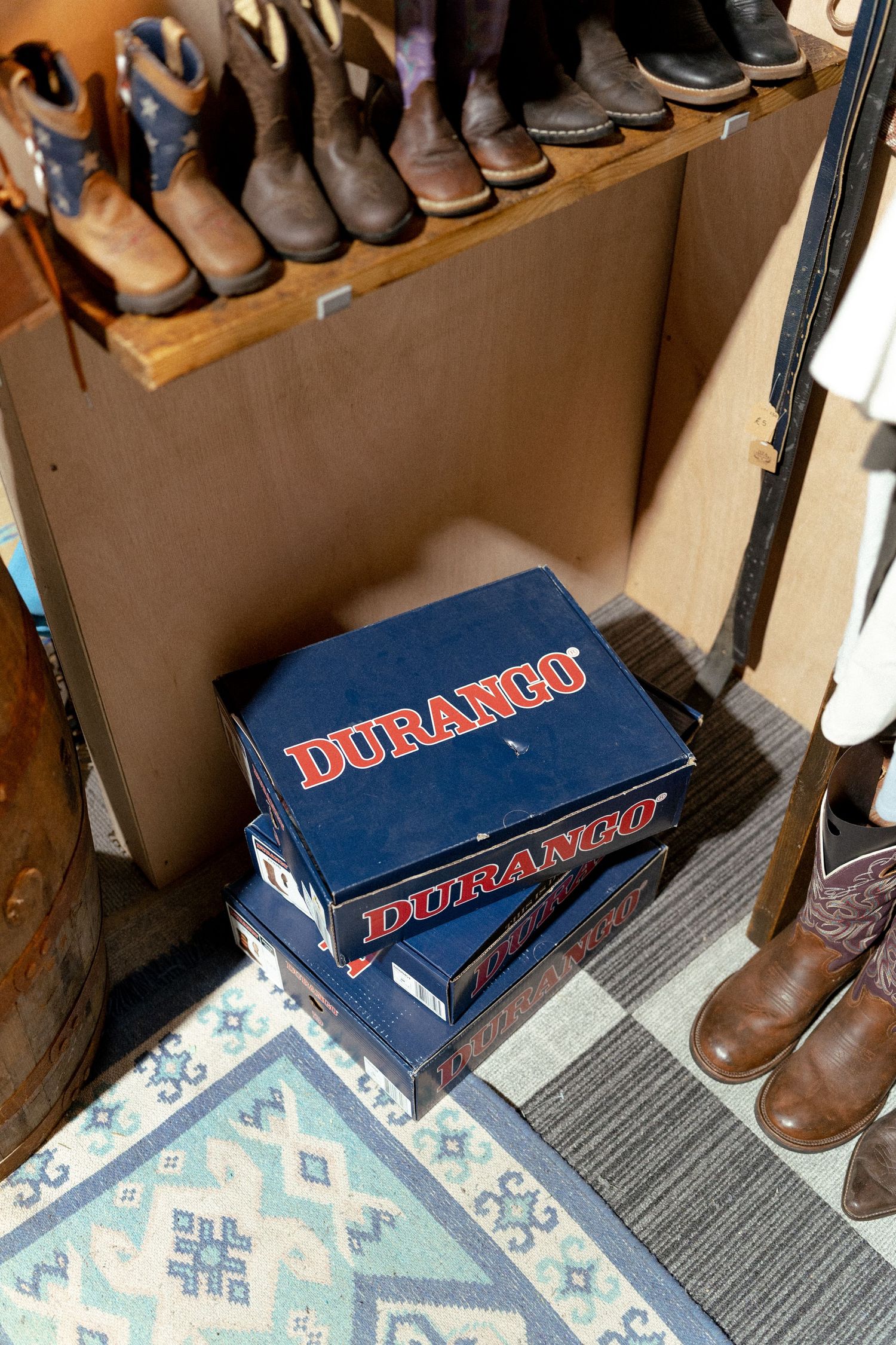 Two Durango boot boxes stacked on a patterned rug in a western boot store with shelves of cowboy boots.