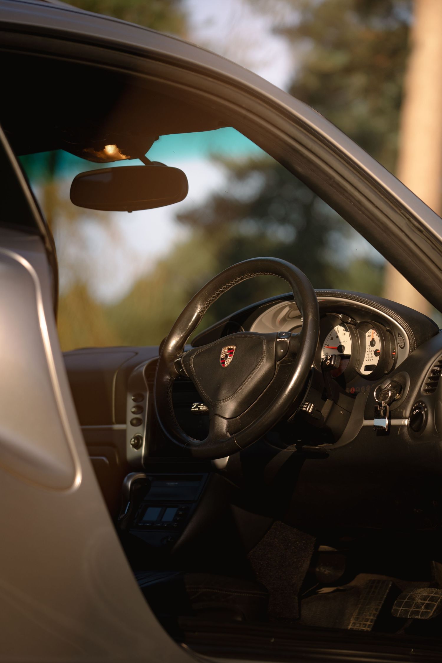 Interior view of a silver Porsche 911 Turbo showing steering wheel, dashboard and gauges.