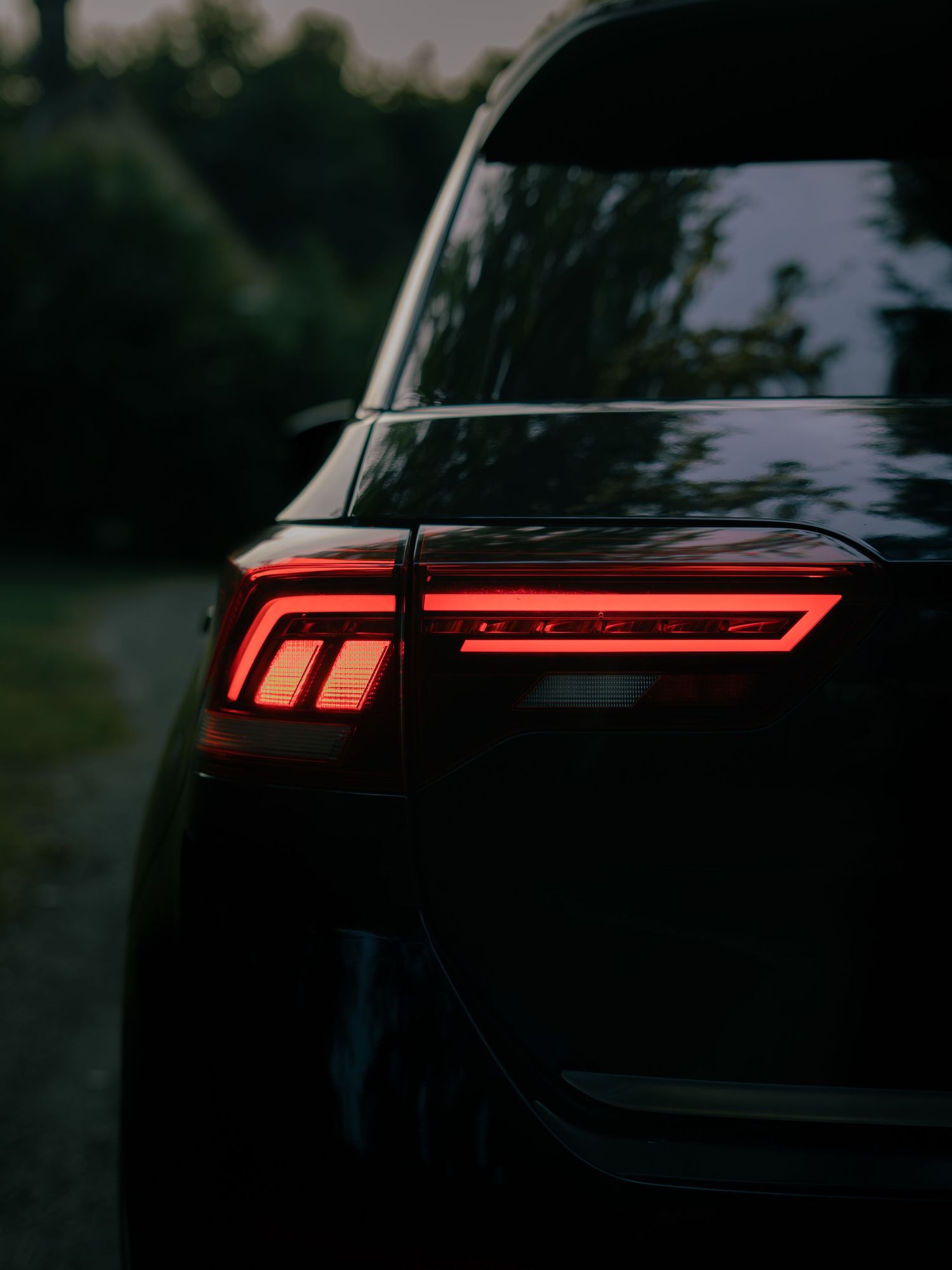 Detailed close-up of striking red LED tail light design on a sleek black SUV.