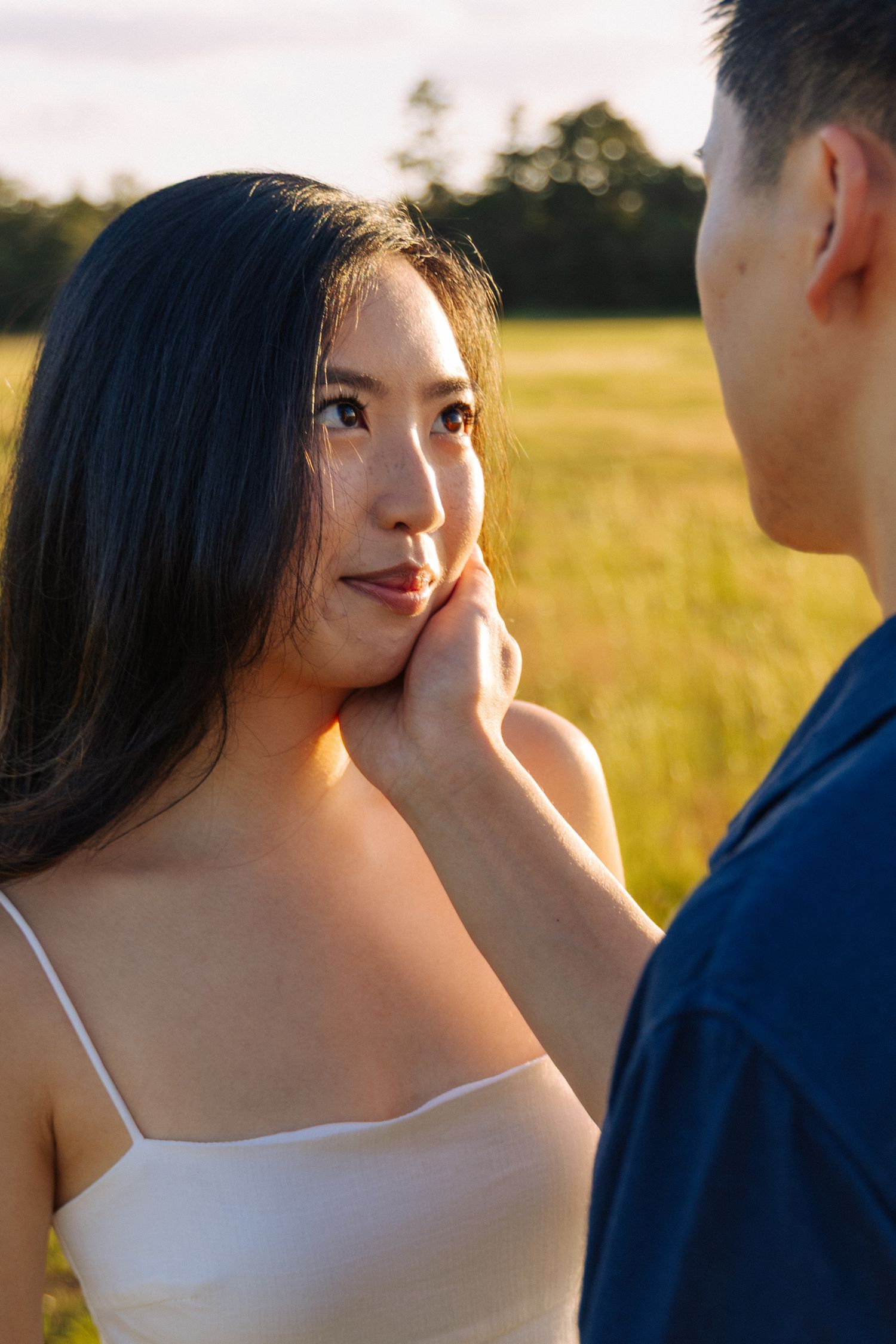 Tender moment between couple during sunset photoshoot in grassy field.
