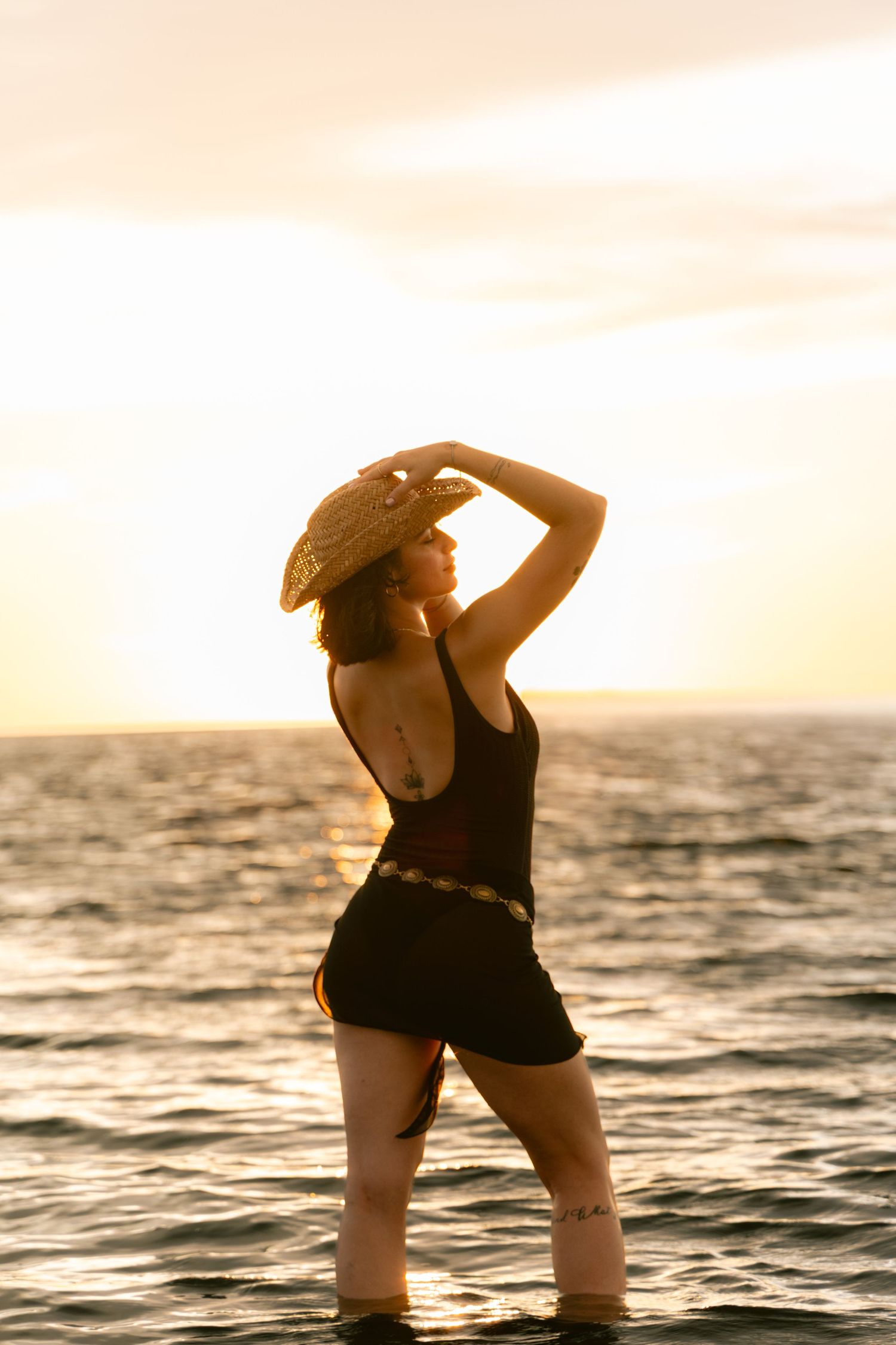 Silhouetted figure poses in water during golden sunset in artistic photo series.