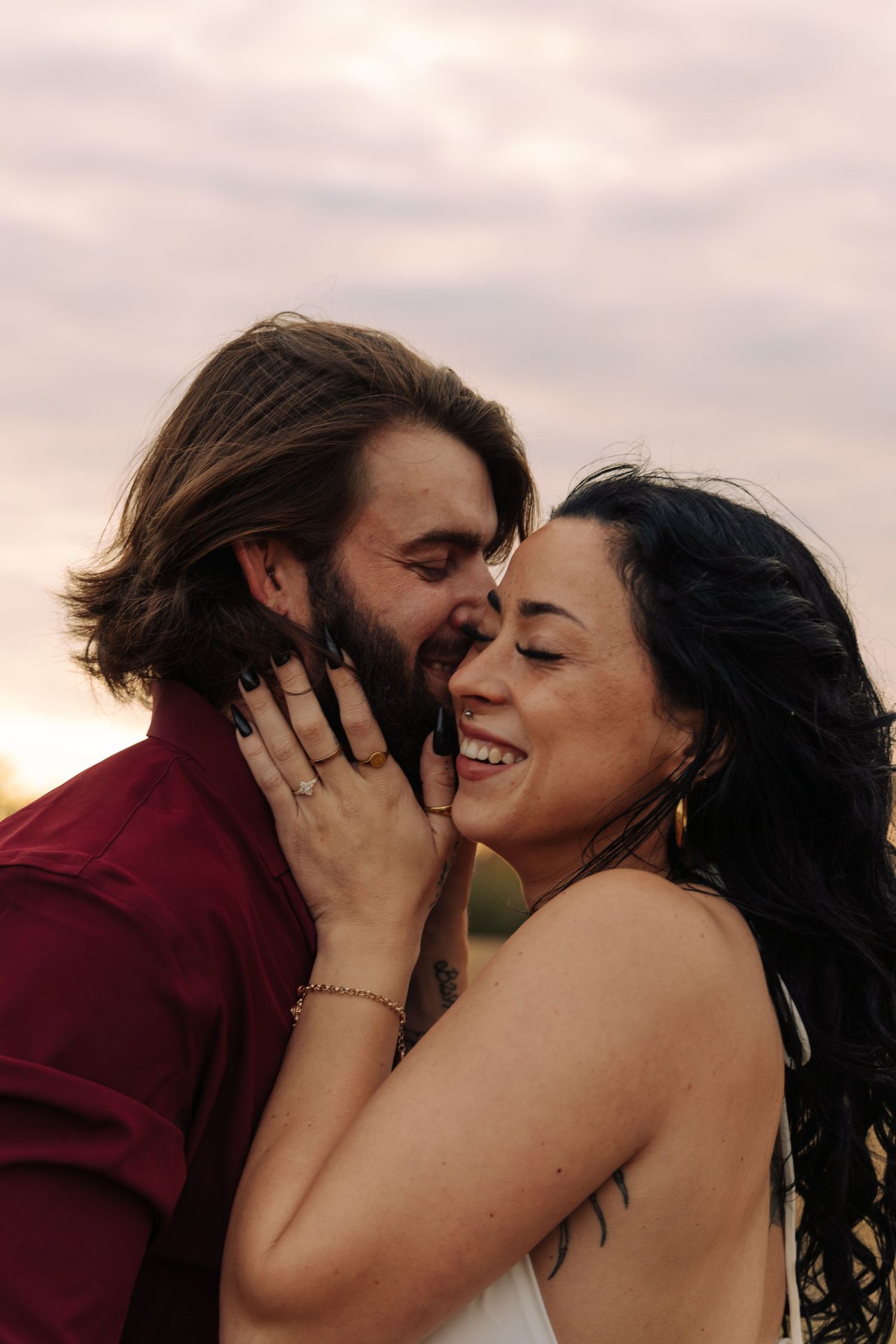 A romantic couple embraces and kisses against a soft sunset sky backdrop in a series of connected photos.